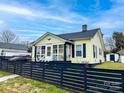 A charming yellow home with black trim, an enclosed porch and a well-kept lawn at 101 Loya St, Mount Holly, NC 28120