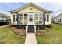 Charming yellow home with a welcoming enclosed porch and well-maintained front yard at 101 Loya St, Mount Holly, NC 28120