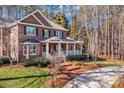 Charming two-story brick home featuring a covered porch, manicured lawn, and mature trees offering privacy and curb appeal at 102 Wyndham Way, Salisbury, NC 28147