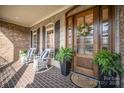 Inviting front porch with seating, stylish door, and potted ferns creating a welcoming entrance at 2028 Fitzhugh Ln, Weddington, NC 28104