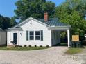 Charming cottage-style home with a manicured lawn, gravel driveway, and a dark green metal roof at 317 Kings Mountain St, York, SC 29745
