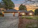 Charming brick home featuring a three-car garage and sunset backdrop, showcasing curb appeal at 805 Stack Rd, Monroe, NC 28112