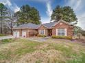 Inviting brick home with manicured lawn, shuttered windows, and three-car garage offering charming curb appeal at 805 Stack Rd, Monroe, NC 28112