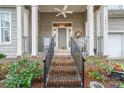 Inviting front porch with brick steps, black railings, and a ceiling fan for outdoor relaxation at 18845 Cloverstone Cir, Cornelius, NC 28031