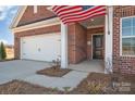 Brick home featuring a two-car garage, an American flag and covered porch at 3069 Founding Fathers Dr # 38, Gastonia, NC 28056