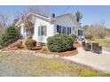 Beautiful landscaping and outdoor seating at this cozy, white single-story home at 4450 Flowes Store Rd, Concord, NC 28025