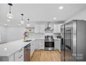 Bright kitchen with stainless steel appliances, quartz countertops, and hardwood floors, perfect for cooking and gatherings at 6301 Vernedale Rd, Charlotte, NC 28212