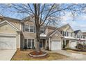 Charming two-story home featuring beige siding, blue shutters, and a well-manicured front yard with a driveway and garage at 11712 Huxley Rd, Charlotte, NC 28277