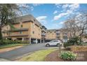 Angle view of a brick condominium complex with mature trees and partial carport parking at 1323 Queens Rd # 202, Charlotte, NC 28207