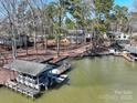 Aerial view of a serene lake house with boat docks and calm waters, perfect for lakeside living at 604 Fairway Shores Rd, Mount Gilead, NC 27306