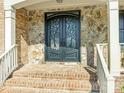 Close-up of an elegant front door with decorative glass and stone accents, complemented by brick steps at 620 Briar Patch Ter, Waxhaw, NC 28173