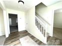 Bright foyer features neutral walls, wood-look floors, a decorative rug, and a carpeted staircase at 9146 Austin Ridge Ln, Charlotte, NC 28214