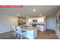 Modern kitchen with a large granite island, stainless steel appliances, and white cabinetry at 107 Windstone Common Ln, Mooresville, NC 28117