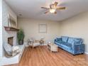 Inviting living room featuring a painted brick fireplace, ceiling fan and hardwood floors at 10901 Carmel Crossing Rd, Charlotte, NC 28226