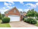 Brick home featuring a two-car garage, manicured lawn, and lush landscaping at 14309 Stonewater Ct, Fort Mill, SC 29707