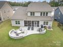 Aerial view of a backyard featuring a stone patio, fire pit, lounge chairs, and screened in porch at 17015 River Race Dr, Huntersville, NC 28078