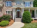 Inviting home entrance with a covered porch, stone accents, and manicured shrubs at 1708 Meadow Crest Ct, Matthews, NC 28104
