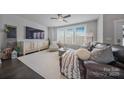 Cozy living room with plush seating, neutral decor, a ceiling fan, and large windows providing ample natural light at 546 Amalfi Dr, Davidson, NC 28036