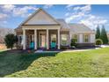 Inviting home with stone-accented porch columns, blue chairs and lush green lawn at 7034 Pin Oaks Dr, Denver, NC 28037