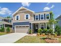 Charming two-story home featuring a covered front porch, attached garage, and manicured lawn at 9843 Quercus Ln, Huntersville, NC 28078