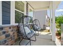 Cozy front porch featuring stylish outdoor seating with decorative pillows and a charming stone accent wall at 9843 Quercus Ln, Huntersville, NC 28078