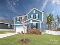 Beautifully landscaped two-story home featuring blue siding, black shutters, a two-car garage, and a well-manicured lawn at 12234 Rowan Hill Dr, Huntersville, NC 28078