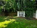 Backyard shed, ideal for extra storage, nestled among mature trees and a partial wooden fence at 14922 Rolling Sky Dr, Charlotte, NC 28273