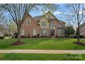 Charming brick home featuring mature trees and expansive grassy front yard at 18334 Dembridge Dr, Davidson, NC 28036