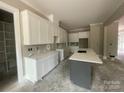 Unfinished kitchen showcasing custom white cabinetry, a gray island, and countertops with white marble accents at 2720 Old Course Rd, Monroe, NC 28112