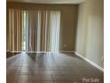 A vacant living room with tile floors, vertical blinds, and a sliding glass door at 300 Orchard Trace Ln # 3, Charlotte, NC 28213