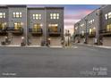 Modern townhomes at dusk featuring attached garages and balconies, set along a paved street at 3750 Ellington St, Charlotte, NC 28211