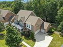 An aerial view showcasing a brick home with a three car garage surrounded by lush trees and greenery at 4708 Pearmain Dr, Waxhaw, NC 28173