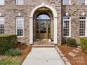 Close-up of arched front door framed by white pillars and brick, complemented by manicured bushes at 5501 Two Iron Dr, Matthews, NC 28104