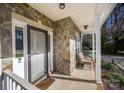 Inviting front porch with stone accents, seating, and a storm door, offering a warm welcome to visitors at 9131 Strattonville Ct, Huntersville, NC 28078