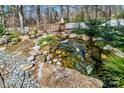 Landscaped backyard featuring a beautiful koi pond with a wooden bridge and rock accents at 1347 Lightwood Dr, Matthews, NC 28105