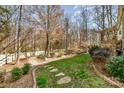 Green backyard with trees, stepping stones, and retaining wall at 1347 Lightwood Dr, Matthews, NC 28105