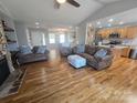 Inviting living room featuring hardwood floors, stone fireplace, and open layout to kitchen and dining areas at 155 Rivercliff Dr, Stony Point, NC 28678