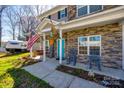 Inviting front porch with rocking chairs and decorative flags accenting a stone facade home at 2375 Ellison Cir, Lancaster, SC 29720