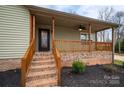 Inviting front porch with brick foundation, wooden railings, and stairs leading to the front door with attractive landscaping at 3155 Ramseur St, Lincolnton, NC 28092