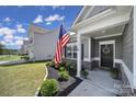 Inviting front porch with American flag, decorative plants, and well-maintained landscaping enhances curb appeal at 325 Ox Bow Cir, Mount Holly, NC 28120