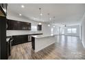 Modern kitchen featuring a granite island, dark cabinets, stainless steel appliances, and hardwood flooring at 325 Ox Bow Cir, Mount Holly, NC 28120