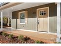 View of front porch that has a concrete slab with a brick border, beige door with a window, and a window with beige shutters at 325 Spring Oak Dr, Salisbury, NC 28147