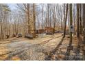 Rustic house surrounded by bare trees with a gravel driveway, car, and utility pole for a private setting at 330 Chinquapin Ln, Mt Ulla, NC 28125