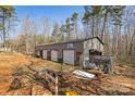 An outbuilding with multiple bays, metal roof, and signage in a wooded yard is ready for use at 330 Chinquapin Ln, Mt Ulla, NC 28125