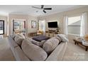 Comfortable living room features neutral tones, a ceiling fan, large windows, and a plush sectional sofa at 430 Battery Cir, Clover, SC 29710