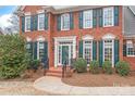 Close-up view of the brick home's entrance, framed by green shutters and manicured landscaping at 4918 Sarah Hall Ln, Charlotte, NC 28270