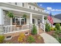 Inviting front porch with white railings, decorative plants, rocking chairs, and a view of the landscaped front yard at 5158 Mill Creek Rd, Clover, SC 29710