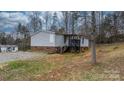 Home exterior with brick foundation, small rear porch with stairs, and gravel driveway at 109 Dogwood Dr, Hickory, NC 28601