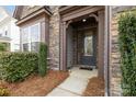Inviting front entrance with stone accents, a covered porch, and a well-lit pathway at 13725 Laughing Gull Dr, Charlotte, NC 28278