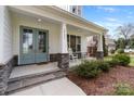 Charming front porch with rocking chairs and stone accents on a light-colored two-story home at 20601 Island Forest Dr, Cornelius, NC 28031